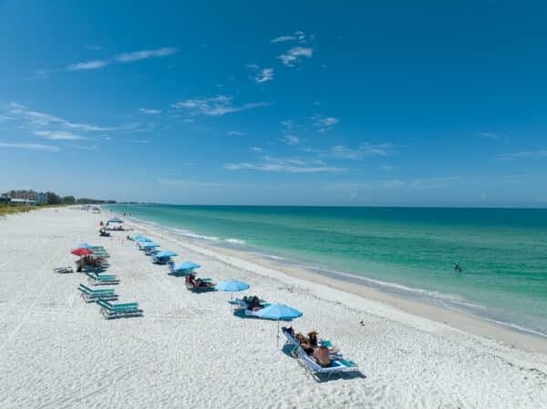 A sunny Florida beach with white sand, turquoise waters, and beach umbrellas, offering a serene and relaxing atmosphere.