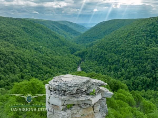 A dramatic rock formation at Lindy Point Overlook with a lush green valley and sunlight breaking through the clouds.